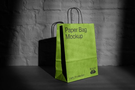 Green paper bag mockup standing on a dark surface against a brick wall background, showcasing design space for branding.